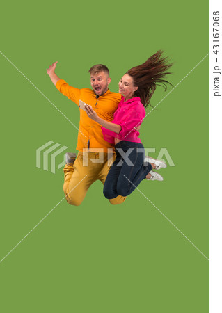 Full length of young couple with mobile phone while jumping Full length of young couple with mobile phone while jumping 43167068
