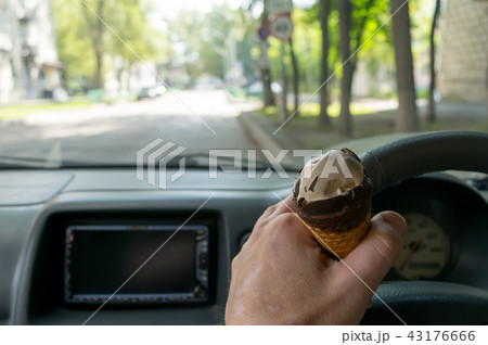driver holds the ice cream while driving a car driver holds the ice cream while driving a car 43176666