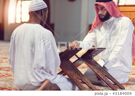 Two religious muslim man praying together inside the mosque Two religious muslim man praying together inside the mosque 43184009