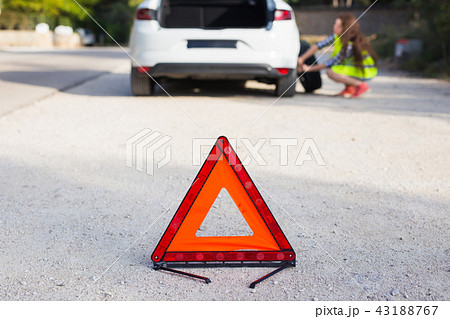 Triangular sign of the accident on the background of a girl about to change the wheel Triangular sign of the accident on the background of a girl about to change the wheel 43188767