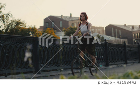 Red haired woman riding bicycle in city on background facade building 43193442