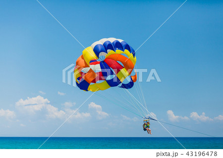 Couple of tourists flying on a colorful parachute Couple of tourists flying on a colorful parachute 43196478