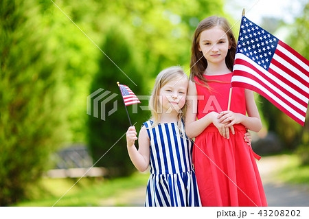 Two adorable little sisters holding american flags 43208202