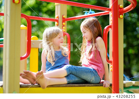 Two cute little girls having fun on a playground Two cute little girls having fun on a playground 43208255