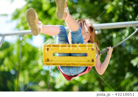 Cute little girl having fun on a playground outdoors in summer Cute little girl having fun on a playground outdoors in summer 43210051