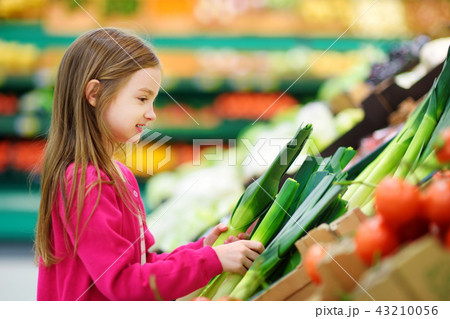 Little girl choosing fresh leek in a food store 43210056
