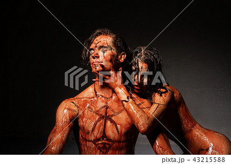 Bloodstained naked couple shot against black wall 43215588