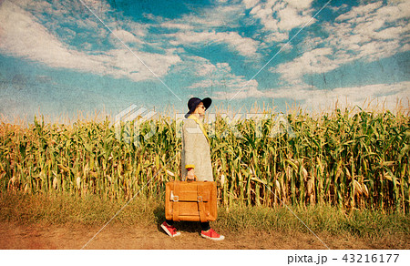 girl coat with suitcase on a rural road near cornfield girl coat with suitcase on a rural road near cornfield 43216177