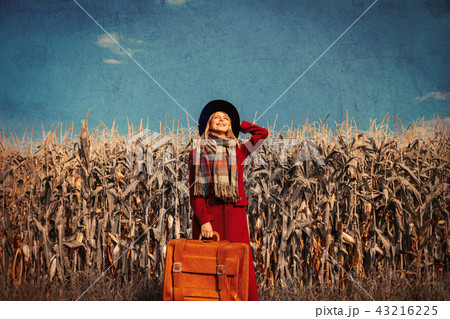 girl coat with suitcase on a rural road near cornfield girl coat with suitcase on a rural road near cornfield 43216225