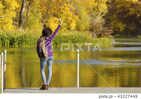 Girl in hat is standing on the pier with her hand Girl in hat is standing on the pier with her hand 43227449