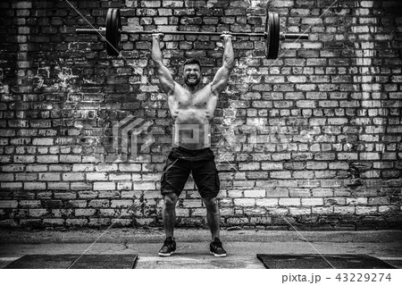 Muscular fitness man doing deadlift a barbell over his head in outdoor, street gym. Functional 43229274