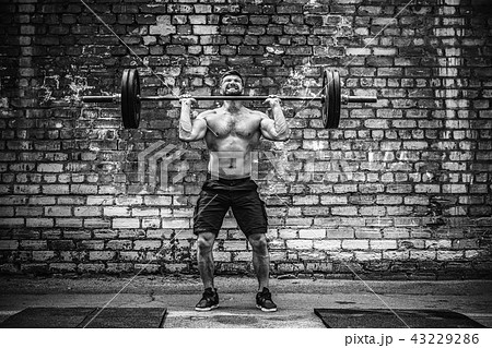 Muscular fitness man doing deadlift a barbell over his head in outdoor, street gym. Functional 43229286