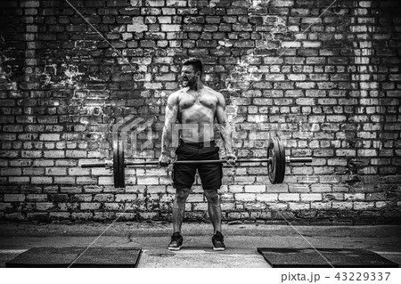 Muscular fitness man doing deadlift a barbell over his head in outdoor, street gym. Functional 43229337