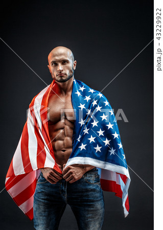 Portrait of bald strong bodybuilder in American flag in studio. Isolated. Portrait of bald strong bodybuilder in American flag in studio. Isolated. 43229922