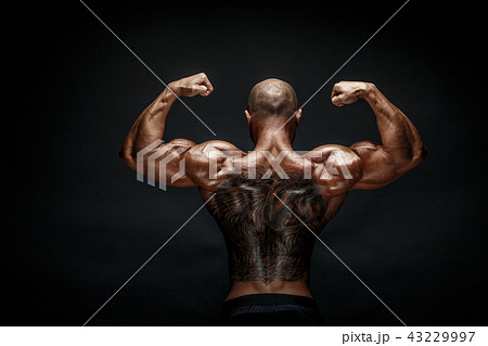Unrecognizable muscular man with tattoo on back against of black background. Isolated. 43229997