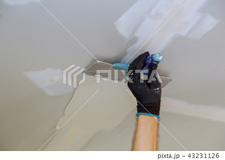Man aligning wall with spatula working with putty Man aligning wall with spatula working with putty 43231126