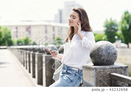 Beautiful woman enjoying music in headphones while walking 43232698