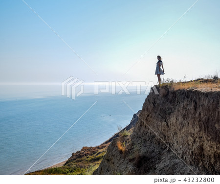 The girl is standing on a cliff near the sea 43232800
