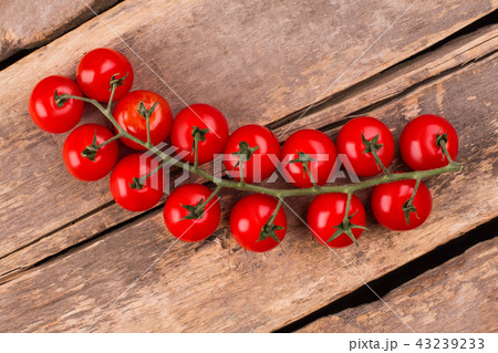 Cherry tomatoes on a branch lie on a rustic table. 43239233