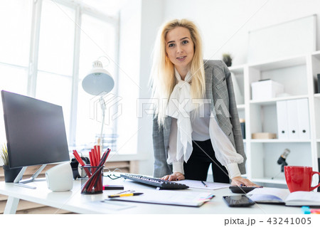A young girl stands in the office, hands on the table. A young girl stands in the office, hands on the table. 43241005