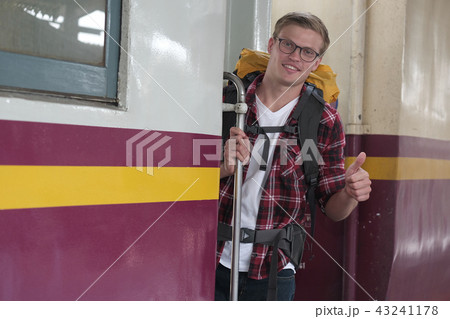 man traveler with backpack shows thumb up on train at railway station. backpacker travel alone. Journey on holiday man traveler with backpack shows thumb up on train at railway station. backpacker travel alone. Journey on holiday 43241178