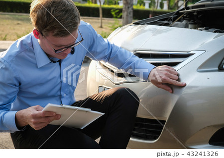 male agent examining car damaged by traffic accident. caucasian man filling auto insurance form. 43241326