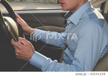 businessman use app on smartphone in car. man holding mobile phone checking direction while driving businessman use app on smartphone in car. man holding mobile phone checking direction while driving 43241339