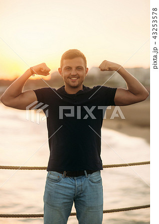 handsome man standing on pier near the sea in sunset time handsome man standing on pier near the sea in sunset time 43253578