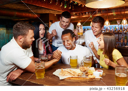 Two handsome male friends having arm wrestling challenge at bar. Two handsome male friends having arm wrestling challenge at bar. 43256918