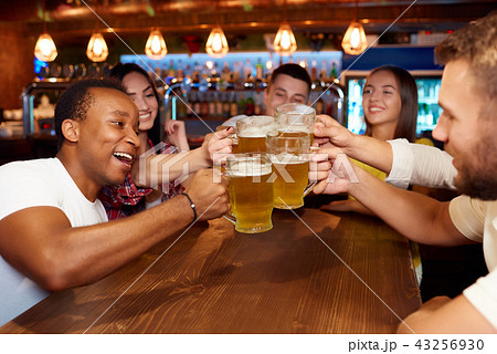 Group of happy friends enjoying beer at pub, toasting and laughing. 43256930