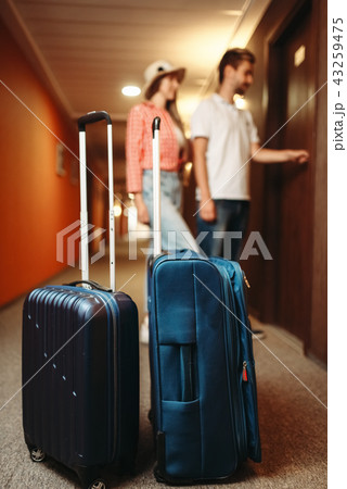 Suitcases in hotel hallway, couple open the door Suitcases in hotel hallway, couple open the door 43259475