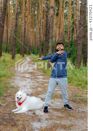 Dark-haired businessman stretching his arms before running in forest Dark-haired businessman stretching his arms before running in forest 43270421