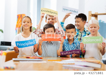 Smiling schoolschildren standing in the middle of a classroom 43271881
