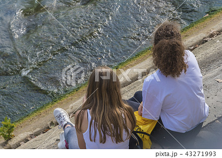 Two youg girls sitting by the river  43271993