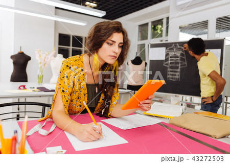 Attentive dressmaker looking at the tablet while drawing Attentive dressmaker looking at the tablet while drawing 43272503