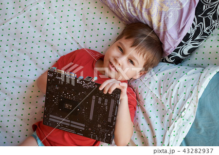 Little boy is playing with a circuit board. 43282937