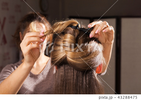 hairdresser making a coiffure with topknot to a model 43288475