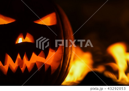 Terrible pumpkin as head of jack-o-lantern with carved eyes and wicked smirk in burning hell fire 43292053