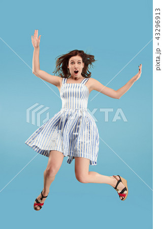 Freedom in moving. Pretty young woman jumping against blue background Freedom in moving. Pretty young woman jumping against blue background 43296913