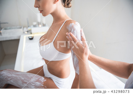 Young woman in white lingerie having skin care procedure with white clay 43298073