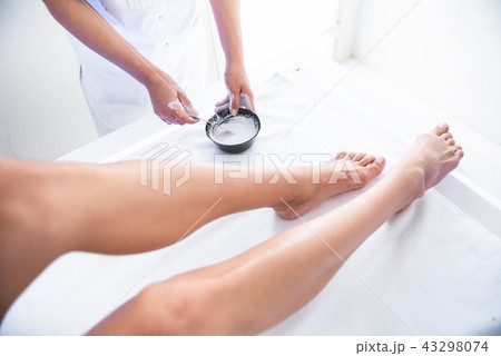 Cosmetologist preparing white clay for procedure while lady lying at spa cabinet 43298074