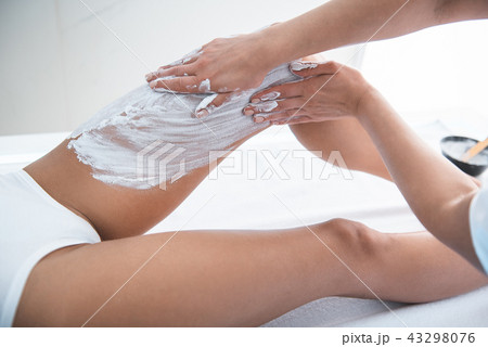 Cosmetologist carefully applying cosmetic mask on lady leg 43298076