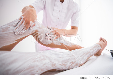 Beautician doing massage with white clay for young lady 43298080