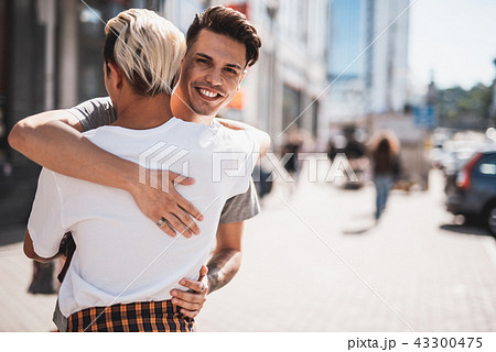 Optimistic guy hugging the comrade at street Optimistic guy hugging the comrade at street 43300475