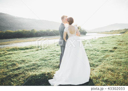 Gorgeous bride and stylish groom walking at sunny landscape, wedding couple, luxury ceremony 43302033