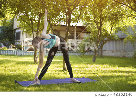 Woman in the garden practices yoga. Pose 43302140