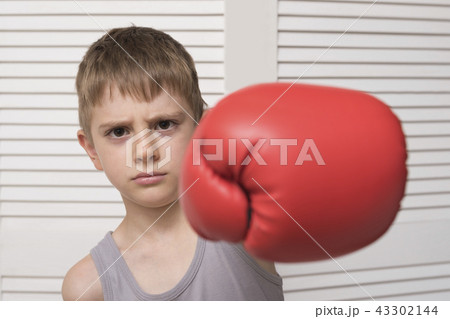 Angry boy in red boxing glove. Hit 43302144