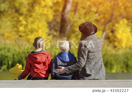 Mom and two children are sitting on the pier Mom and two children are sitting on the pier 43302227
