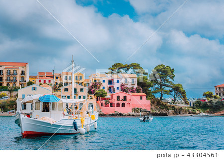 View of beautiful bay of Assos village with fishing boat at anchor in front and clouds in background View of beautiful bay of Assos village with fishing boat at anchor in front and clouds in background 43304561