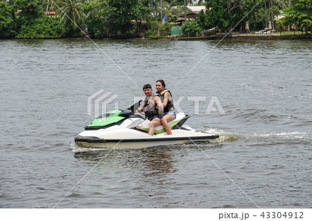 Happy young couple having fun riding on a jet ski Happy young couple having fun riding on a jet ski 43304912